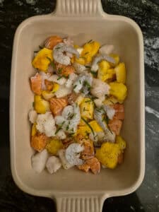 Fish in cooking dish, along with chives and seasoning