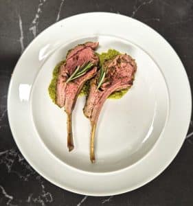 Herb-crusted rack of lamb -2 bones on a plate served on a bed of pea puree