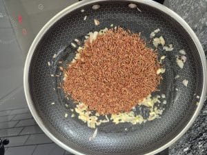 Rice toasting with garlic and shallots in a pan