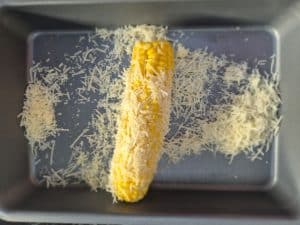 Roll the corn of the cob with mayo in the parmasan